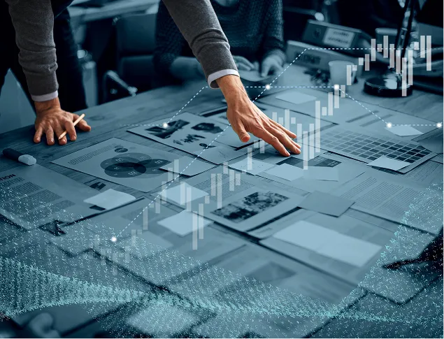 Person analyzing business charts and data sheets with digital financial graphs overlay.