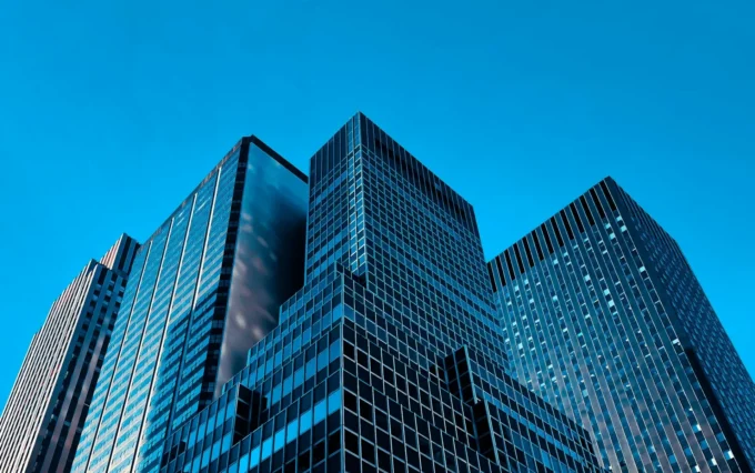 Cluster of modern glass skyscrapers under a clear blue sky, reflecting light.
